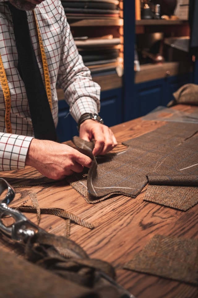 Tailor measuring and marking pattern on fine fabric with chalk